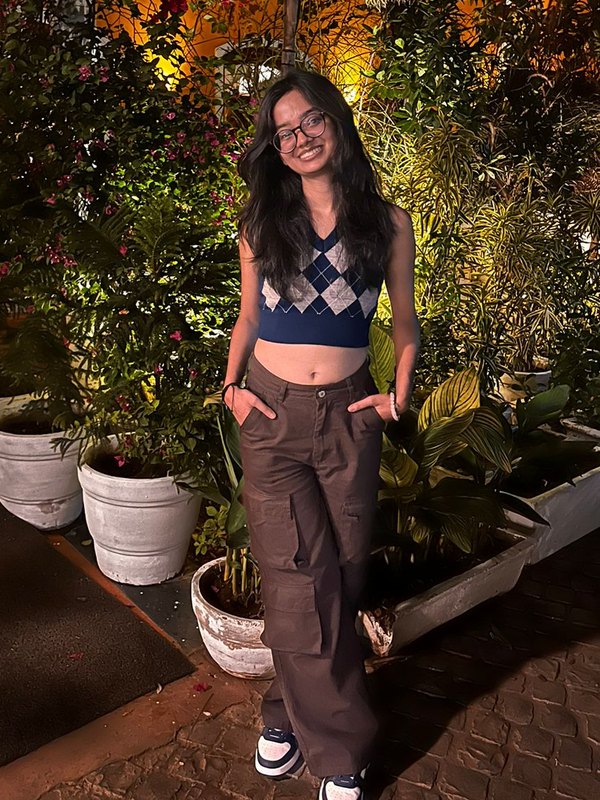 Portrait of Ishika Singh smiling, standing among plants in warm evening light